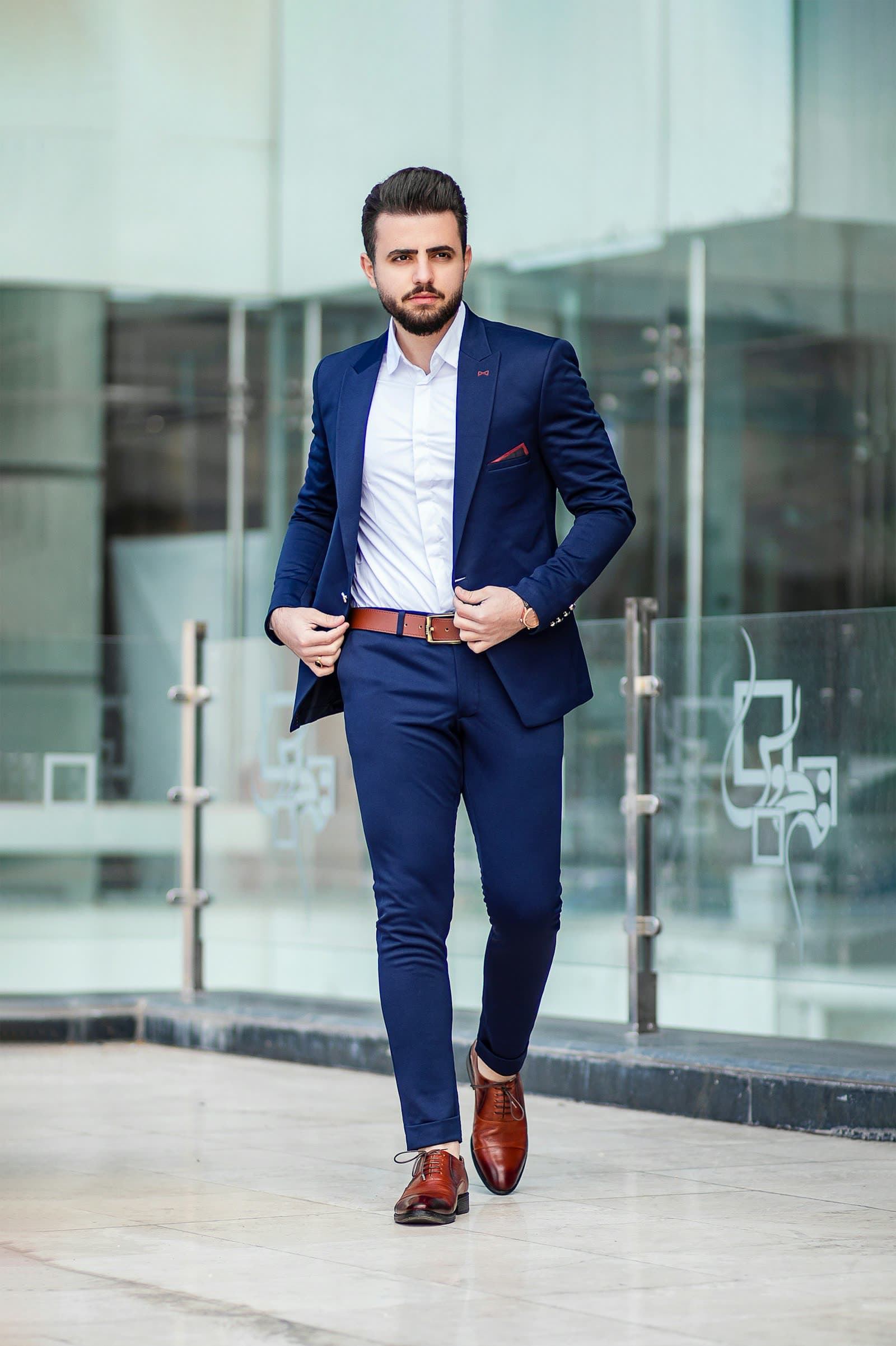 Man in a dark tailored suit standing in warm interior light